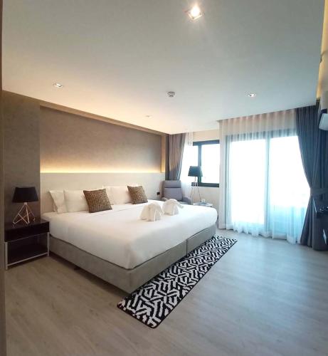 a bedroom with a large white bed with a rug at The 9 Residence Hotel in Bangkok