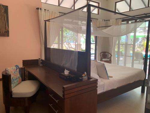 a bedroom with a canopy bed with a desk and a chair at Ban Laem Set - by Sublime Samui Villas in Laem Set Beach