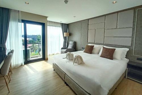 a large white bed in a room with a large window at The 9 Residence Hotel in Bangkok