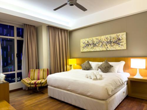 Cormar KLCC Suites By NHB في كوالالمبور: غرفة نوم بسرير ابيض كبير وكرسي
