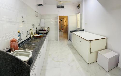 a white kitchen with a sink and a counter at Cozy 1 BHK Apartment in Nagpur