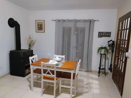 a dining room with a table and chairs and a stove at Maison cocooning in Lhommaizé