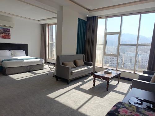 een hotelkamer met een bed, een bank en een stoel bij Hill Top Muscat in Muscat