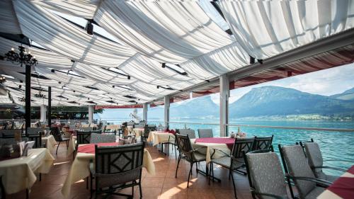 a restaurant with tables and chairs and a view of the water at Romantik Residenz (Ferienwohnungen Hotel Im Weissen Rössl) - Dependance in St. Wolfgang