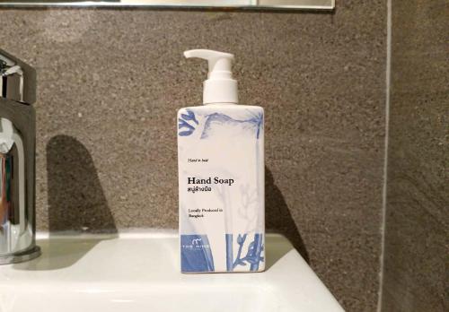 a bottle of hand soap sitting on top of a sink at The 9 Residence Hotel in Bangkok
