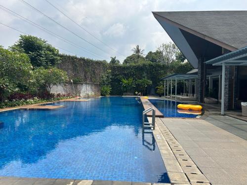 a large blue swimming pool next to a house at Five Leo’s villa in Gadok 1