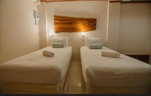 2 bedden in een kamer met witte lakens bij โรงแรมริเวอร์เลย แกรนด์วิว in Wang Saphung