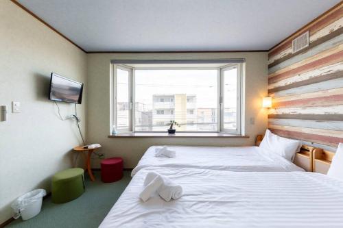 a hotel room with two beds and a window at Sprinkle inn in Sapporo