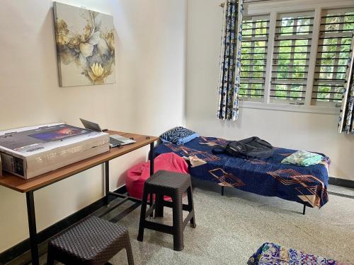 um quarto com uma secretária, uma cama, uma mesa e uma cadeira. em Luxury Queen Bed Suite 6km to Palace with Farm Land and Hill View em Mysore