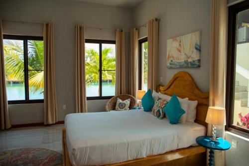 een slaapkamer met een wit bed en uitzicht op het water bij Island Time Gecko in Placencia Village