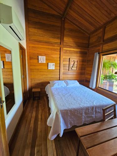 塞古羅港的住宿－Chalé do Beco - Nova Caraíva，木制客房内的一间卧室,配有一张床