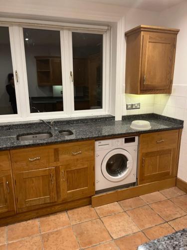 a kitchen with a washing machine and a window at The barn in Croydon