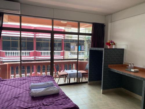 a bedroom with a purple bed and a balcony at Chai Ben guesthouse in Jomtien Beach