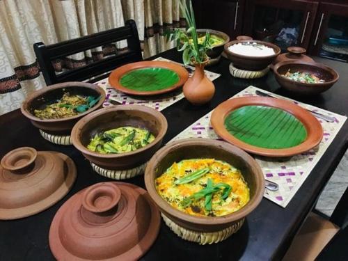 a table topped with bowls and plates of food at Ayubowan Homestay Katunayake in Katunayake