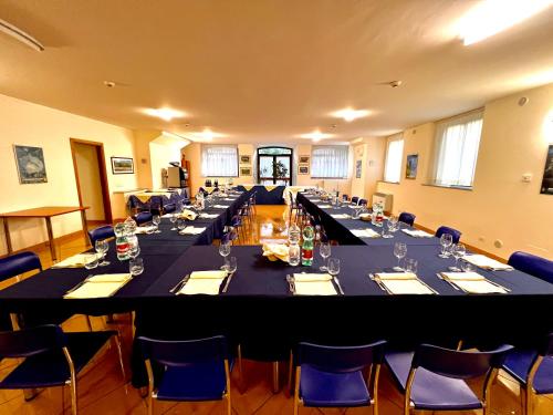 une grande salle de conférence avec de longues tables et des chaises bleues dans l'établissement Nazareth Residence, à Viterbe