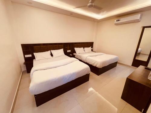 Habitación de hotel con 2 camas con sábanas blancas en White House - A Four Star Luxury Resort, en Haridwar