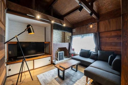 a living room with a couch and a tv at YADOt Inn OTARU in Otaru