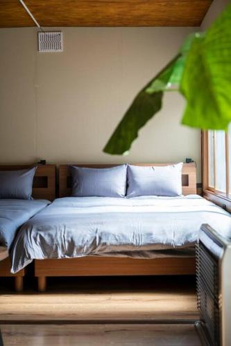 a bedroom with a bed with blue pillows and a window at YADOt Inn OTARU in Otaru