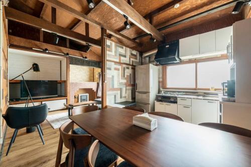 a kitchen and dining room with a wooden table and chairs at YADOt Inn OTARU in Otaru