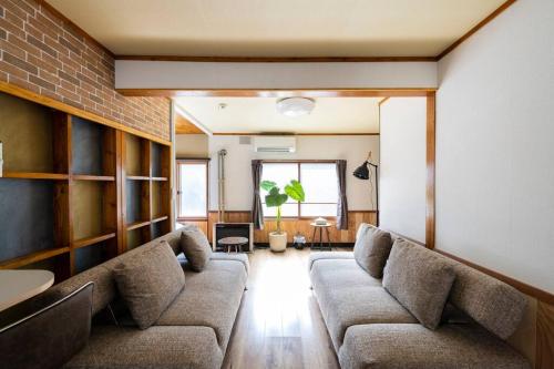 a living room with a couch and a brick wall at YADOt Inn OTARU in Otaru