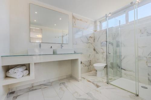 een witte badkamer met een wastafel en een douche bij Sunrise Zante - Adults Only Hotel in Tsilivi