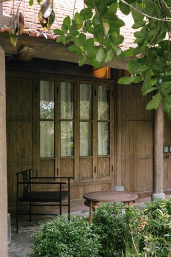 a wooden porch with a bench and a table at TOKI Retreat Vân Long in Ninh Binh