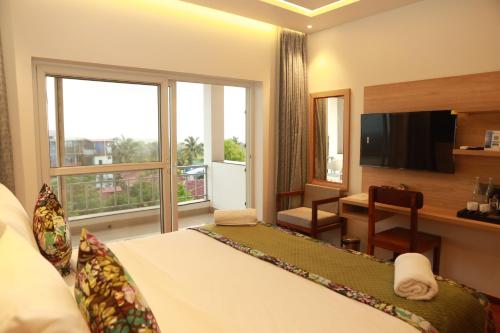 モージムにあるGracias Cafe & Resortのベッド、デスク、窓が備わるホテルルームです。