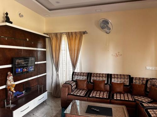 a living room with a couch and a tv at DEEYA Guest House - A Luxury Home Stay in Mysore