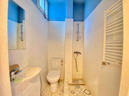 a white bathroom with a toilet and a sink at S+1 au cœur de la Marsa plage in La Marsa