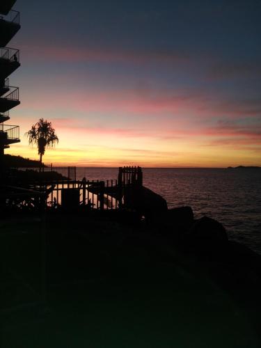 a sunset over the ocean with a pier and a tree at Panoramic Ocean Views 2 bed/2 bath Unit, Nelly Bay in Nelly Bay