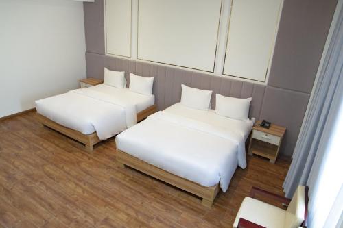 two beds in a room with white sheets at The Mansion Hotel Bien Hoa in Bien Hoa