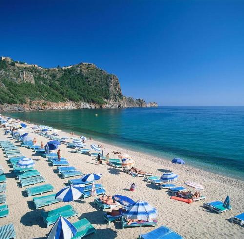 una playa con sombrillas azules y blancas y el océano en Palm Beach Cleopatra House, beautiful private apartment just 200 meters to cleopatra beach 14 with umbrellas, bikes and many extras included! EUR 300 Cashback for 2-3 months rental!, en Alanya