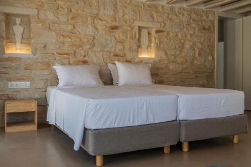 a bed in a room with a stone wall at Aegean Feelings in Piso Livadi