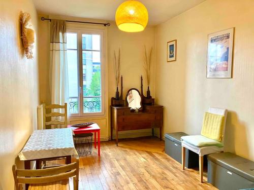 uma sala de estar com uma mesa e cadeiras e uma janela em Charmant appartement 1930 Centre-ville Nogent-sur-Marne em Nogent-sur-Marne