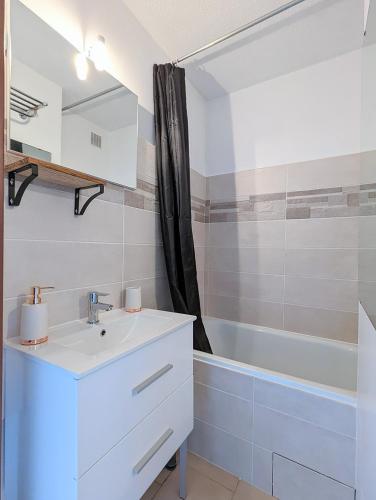 une salle de bain avec un lavabo et une baignoire dans l'établissement Appartement au CALME + parking, au Cap d'Agde