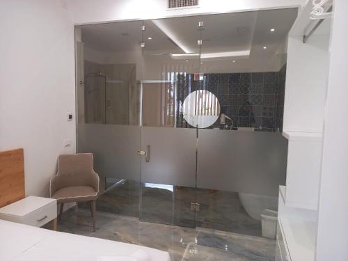 een badkamer met een glazen douche en een stoel bij Jonium Hotel Residence in Pulsano