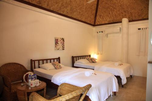 two beds in a room with a table and chairs at Sunz en Coron Resort in Coron