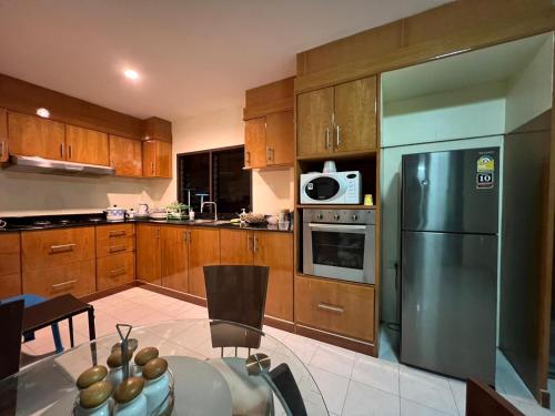 a kitchen with wooden cabinets and a stainless steel refrigerator at Hideaway House Patong in Patong Beach
