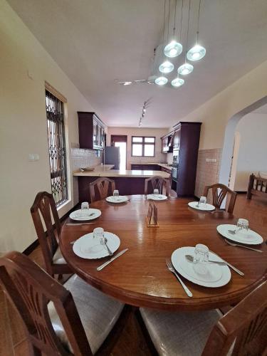 a large wooden table with chairs and a kitchen at Marique villa in Mombasa