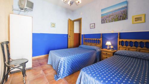 a bedroom with two beds and a chair in it at Casa Rural La Fragua de Manuel in Pelahustán