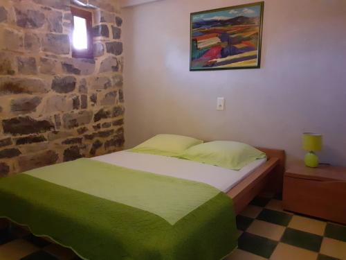 Un dormitorio con una cama y una pared de piedra. en Gîte L'ESCOUSSOU 6p, 4ch, 120m2, charme et nature, piscine chauffée, sud Ardèche, en Joyeuse