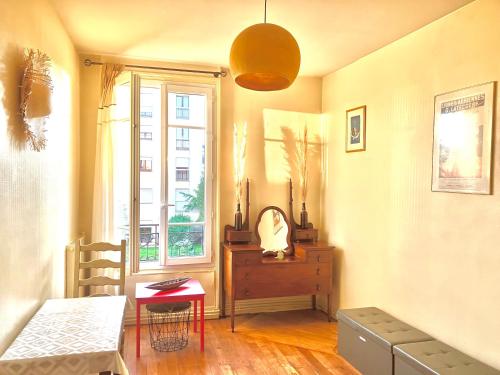 uma sala de estar com uma mesa e uma janela em Charmant appartement 1930 Centre-ville Nogent-sur-Marne em Nogent-sur-Marne