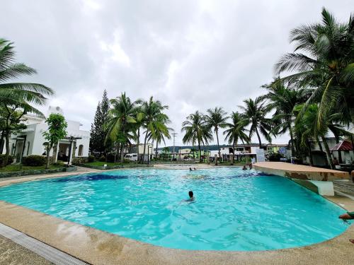 a person swimming in a large pool with palm trees at Calapan City Cheapest House Transient Guest Rental L39 in Calapan