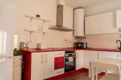 a kitchen with red and white cabinets and a table at Increíble Duplex luminoso, plaza del Aymto. in Talavera de la Reina