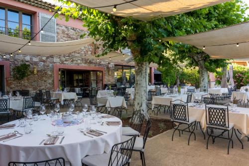 - un coin repas extérieur avec des tables blanches, des chaises et des arbres dans l'établissement La Bastide Du Clos des Roses - Teritoria, à Fréjus