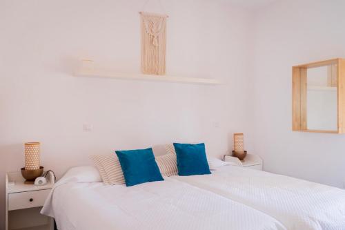 una camera da letto con un letto bianco con cuscini blu di Apartamentos Entreteatros, fantástico duplex casco histórico a Talavera de la Reina