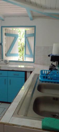 eine Küchentheke mit einem Waschbecken und einem Fenster in der Unterkunft La Creoline 01 in Pointe-Noire