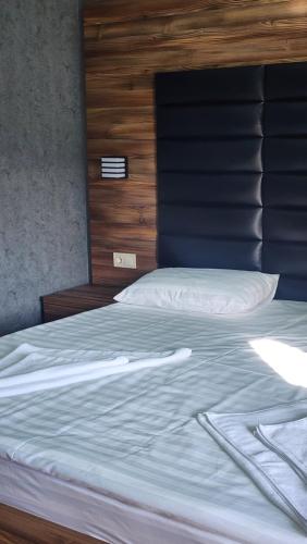 a large bed with white sheets and a wooden headboard at Luxor Rabath in Akhaltsikhe