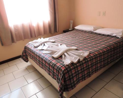 a bedroom with a bed with towels on it at HsHotelaria - Filial Bombinhas in Bombinhas