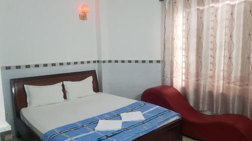 a bedroom with a bed and a red chair at Khách sạn Hoàng Long in Ho Chi Minh City